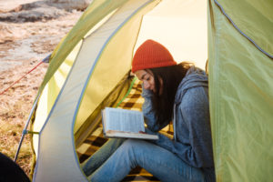 Woman reading a book inside a tent